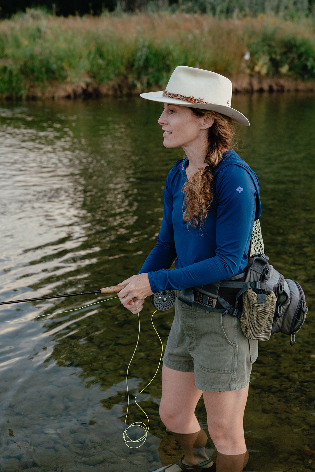 Sunshirt_Marine_Blue_Woman fly fishing by a body of water