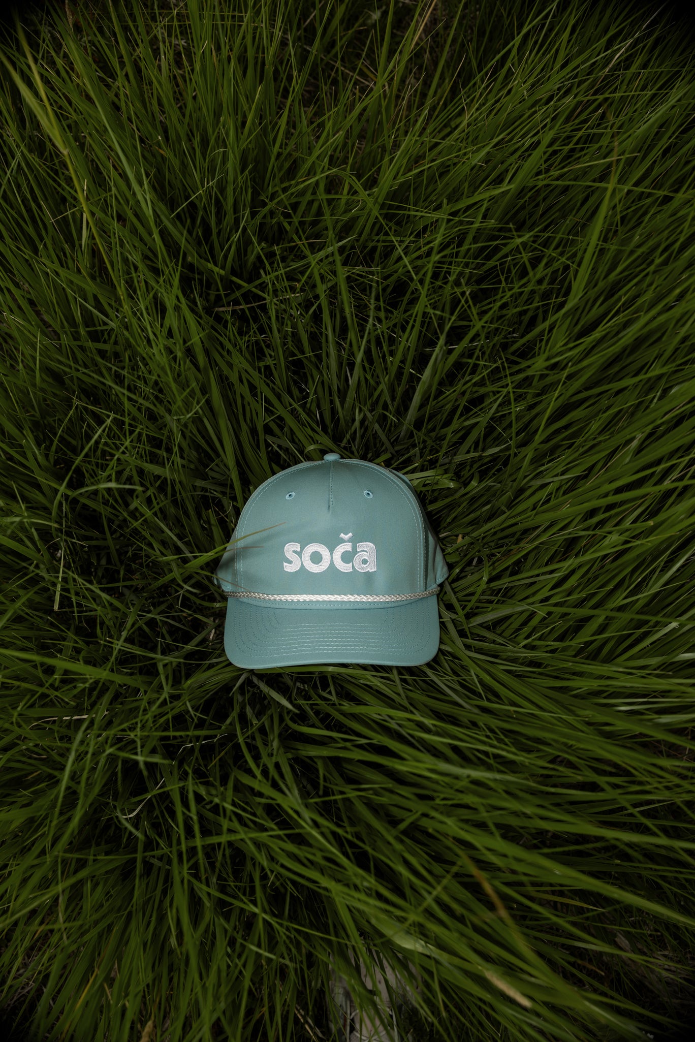 dusty blue cap with 'soča' logo on grass